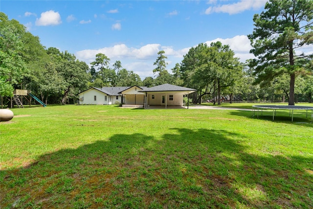 33933 Deer Creek Way, Stagecoach, TX 77355 - view of green lawn featuring a trampoline, a playground, view of scattered trees, and a patio area