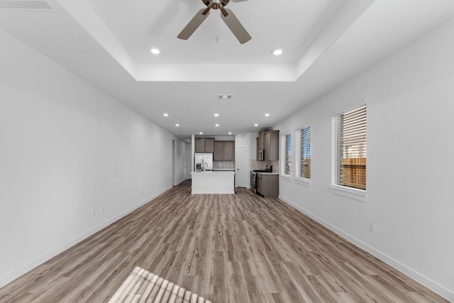 19376 Poppy Village Cir, Magnolia, TX 77355 - unfurnished living room featuring light wood-style flooring, recessed lighting, ceiling fan, and a tray ceiling