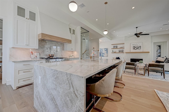 1506 W 43rd St, Houston, TX 77018 - kitchen with light wood finished floors, white cabinets, light stone counters, backsplash, and a ceiling fan