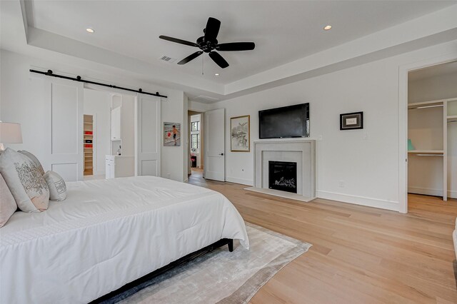 1506 W 43rd St, Houston, TX 77018 - bedroom featuring a spacious closet, a barn door, a raised ceiling, light wood-style floors, and recessed lighting