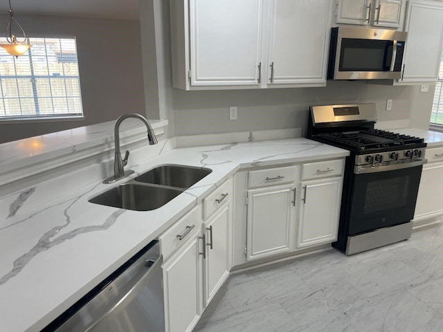 9311 Rippling Fields Dr, Houston, TX 77064 - kitchen with stainless steel appliances, white cabinetry, light stone counters, and hanging light fixtures