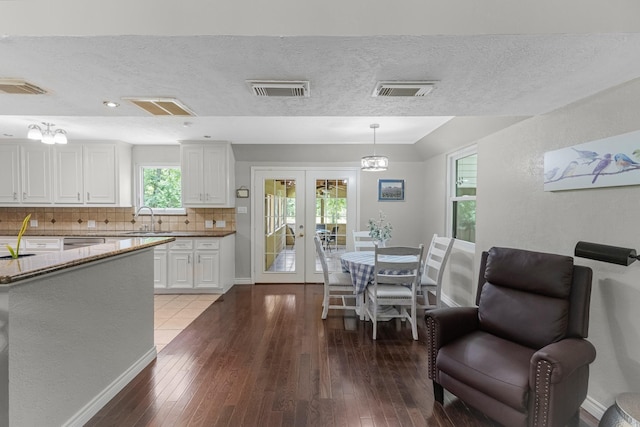 8918 James Ct, Magnolia, TX 77354 - kitchen featuring backsplash, light wood-type flooring, white cabinets, french doors, and a textured ceiling