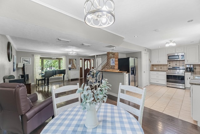 8918 James Ct, Magnolia, TX 77354 - dining room with light wood-style floors, crown molding, and stairs