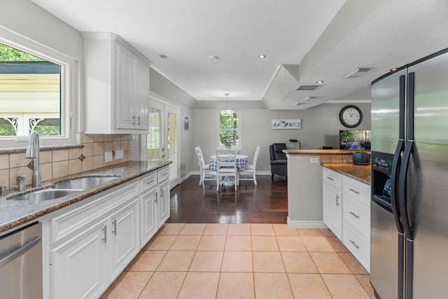 8918 James Ct, Magnolia, TX 77354 - kitchen featuring stainless steel appliances, backsplash, white cabinetry, dark stone counters, and light tile patterned floors