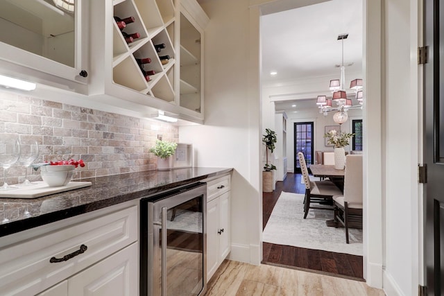1022 W 22nd St, Houston, TX 77008 - indoor bar featuring wine cooler, a chandelier, decorative backsplash, light wood-style floors, and decorative light fixtures