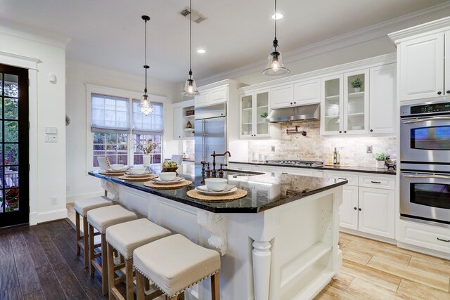 1022 W 22nd St, Houston, TX 77008 - kitchen featuring stainless steel appliances, open shelves, under cabinet range hood, decorative backsplash, and white cabinetry