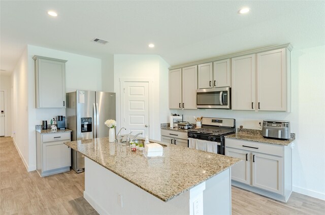 31714 Brandon Mill Trl, Fulshear, TX 77441 - kitchen with appliances with stainless steel finishes, light wood-style flooring, light stone countertops, an island with sink, and recessed lighting