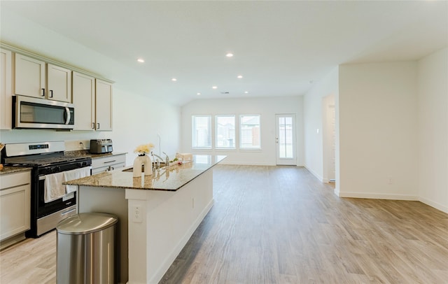 31714 Brandon Mill Trl, Fulshear, TX 77441 - kitchen featuring stainless steel appliances, light wood-type flooring, light stone counters, open floor plan, and an island with sink