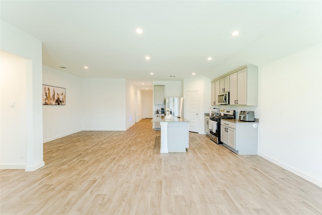 31714 Brandon Mill Trl, Fulshear, TX 77441 - kitchen with appliances with stainless steel finishes, open floor plan, recessed lighting, light wood-style flooring, and an island with sink