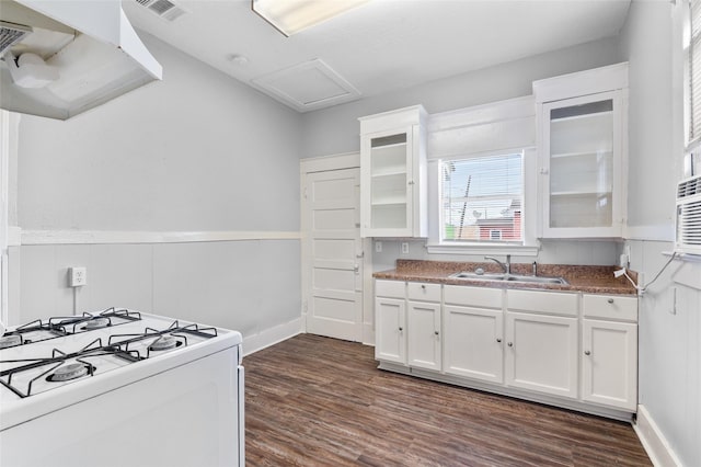 714 44th St, Galveston, TX 77550 - kitchen featuring white gas range oven, dark wood-style flooring, white cabinets, glass insert cabinets, and a wainscoted wall