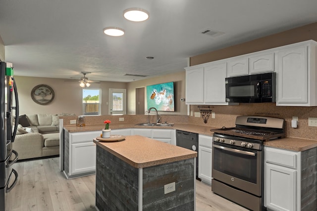 926 Seabourne Meadows Dr, Rosenberg, TX 77471 - kitchen with black appliances, a peninsula, open floor plan, light wood-type flooring, and white cabinetry