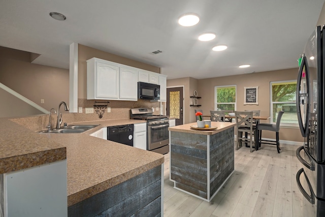 926 Seabourne Meadows Dr, Rosenberg, TX 77471 - kitchen featuring black appliances, white cabinets, a center island, light wood finished floors, and recessed lighting