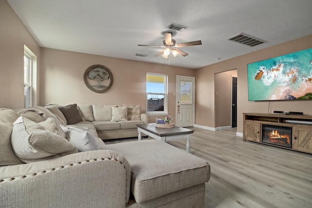 926 Seabourne Meadows Dr, Rosenberg, TX 77471 - living room with light wood-type flooring, a ceiling fan, and a glass covered fireplace