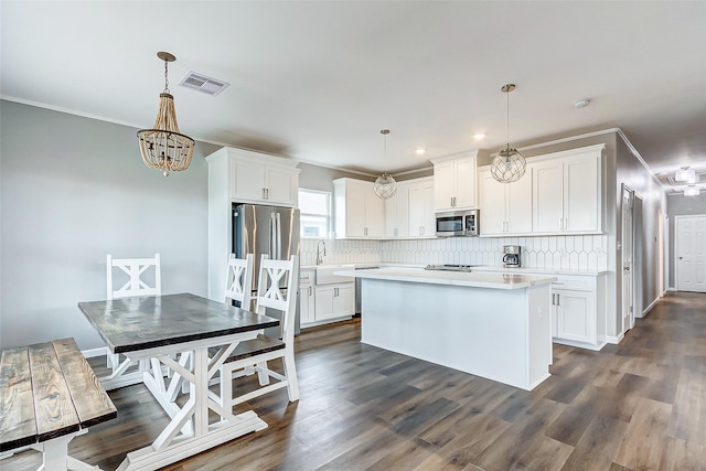1743 Blue Water Hwy, Surfside Beach, TX 77541 - kitchen with appliances with stainless steel finishes, light countertops, decorative backsplash, white cabinetry, and crown molding