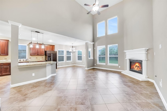 6222 Deer Run Xing, Katy, TX 77493 - unfurnished living room with ceiling fan, a chandelier, a glass covered fireplace, a high ceiling, and light tile patterned flooring