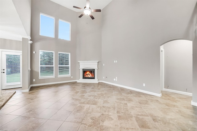 6222 Deer Run Xing, Katy, TX 77493 - unfurnished living room featuring a high ceiling, ceiling fan, arched walkways, a glass covered fireplace, and light tile patterned floors