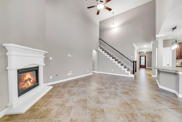 6222 Deer Run Xing, Katy, TX 77493 - unfurnished living room with a ceiling fan, a high ceiling, a glass covered fireplace, stairway, and light tile patterned flooring