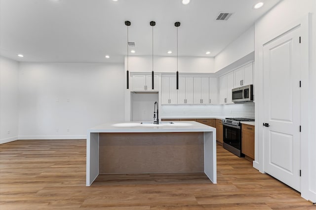 507 Middle St, Houston, TX 77003 - kitchen with appliances with stainless steel finishes, light wood-type flooring, light countertops, decorative backsplash, and hanging light fixtures