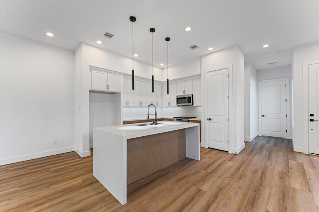507 Middle St, Houston, TX 77003 - kitchen with stainless steel appliances, tasteful backsplash, light countertops, light wood-style flooring, and white cabinets