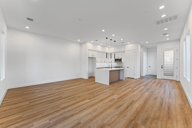 507 Middle St, Houston, TX 77003 - kitchen featuring stainless steel microwave, open floor plan, an island with sink, light wood finished floors, and recessed lighting