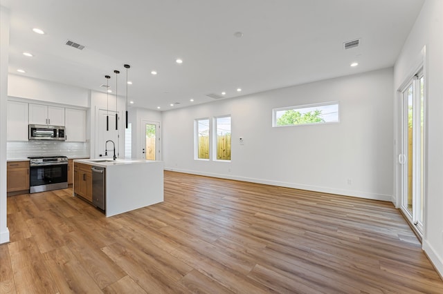 507 Middle St, Houston, TX 77003 - kitchen featuring stainless steel appliances, open floor plan, light countertops, light wood-type flooring, and backsplash
