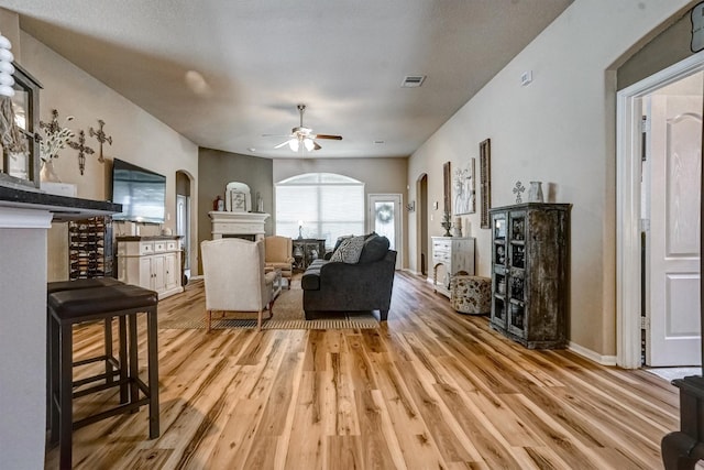 21714 Venture Park Dr, Richmond, TX 77406 - living area with arched walkways, light wood-type flooring, a fireplace, and ceiling fan