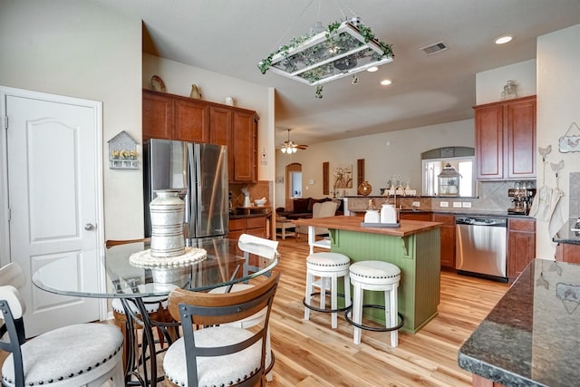 21714 Venture Park Dr, Richmond, TX 77406 - kitchen featuring stainless steel appliances, backsplash, light wood-style flooring, a kitchen breakfast bar, and brown cabinets