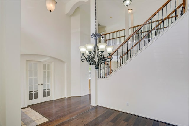 13508 Sweet Wind Ct, Pearland, TX 77584 - unfurnished dining area with arched walkways, a high ceiling, dark wood-style floors, a chandelier, and french doors