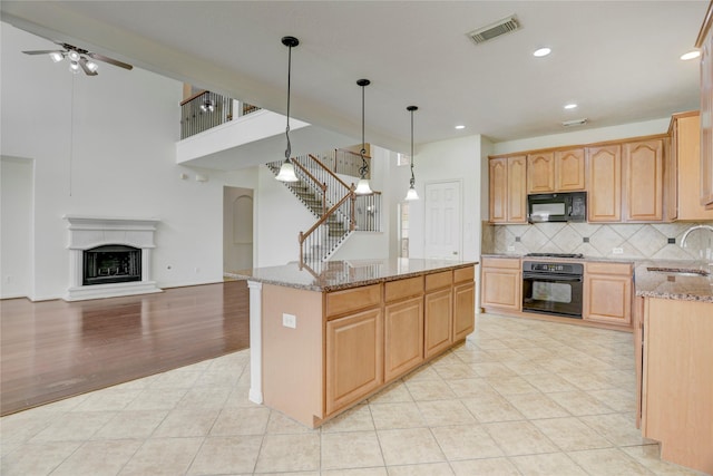 13508 Sweet Wind Ct, Pearland, TX 77584 - kitchen featuring black appliances, light stone counters, backsplash, open floor plan, and a kitchen island