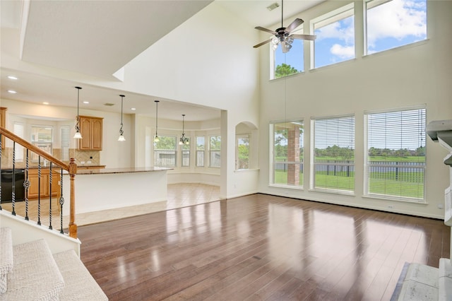 13508 Sweet Wind Ct, Pearland, TX 77584 - unfurnished living room with plenty of natural light, ceiling fan, a towering ceiling, light wood finished floors, and stairway