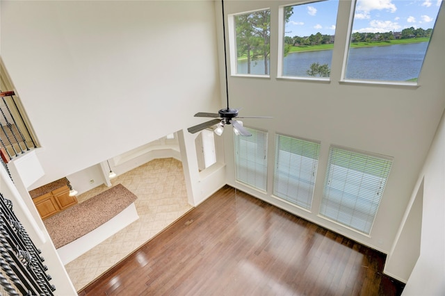 13508 Sweet Wind Ct, Pearland, TX 77584 - unfurnished living room with ceiling fan, hardwood / wood-style flooring, a water view, and a high ceiling