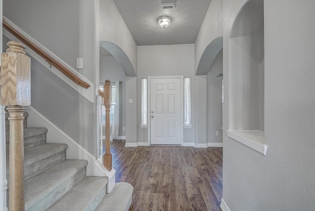 8014 Pine Wood Ct, Baytown, TX 77523 - entryway with arched walkways, wood finished floors, stairs, and a textured ceiling