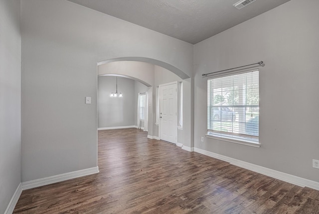 8014 Pine Wood Ct, Baytown, TX 77523 - empty room featuring arched walkways, dark wood-style floors, and a chandelier