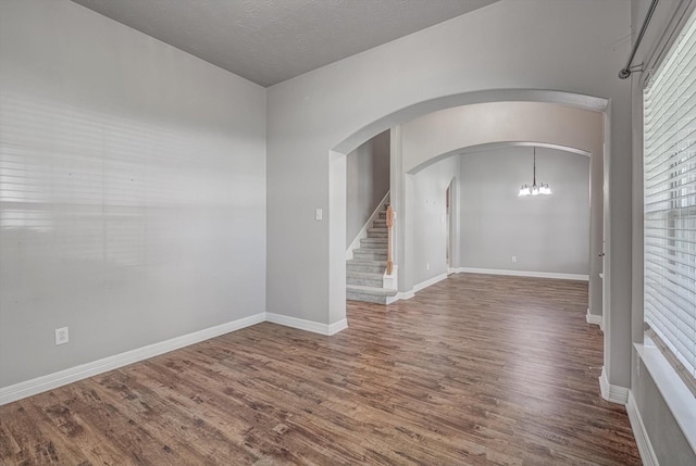 8014 Pine Wood Ct, Baytown, TX 77523 - spare room featuring wood finished floors, arched walkways, stairway, and a chandelier