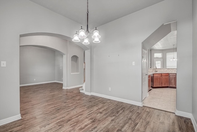 8014 Pine Wood Ct, Baytown, TX 77523 - spare room with a chandelier, light wood-type flooring, and arched walkways