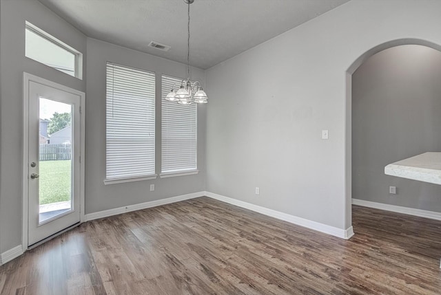 8014 Pine Wood Ct, Baytown, TX 77523 - unfurnished dining area featuring wood finished floors, arched walkways, healthy amount of natural light, and a chandelier