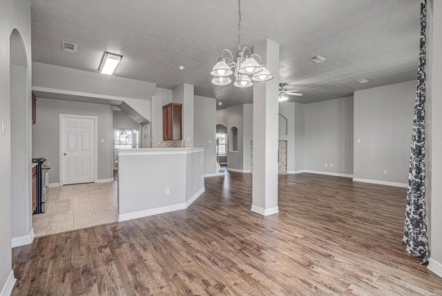 8014 Pine Wood Ct, Baytown, TX 77523 - unfurnished living room featuring arched walkways, a ceiling fan, light wood-type flooring, plenty of natural light, and a textured ceiling