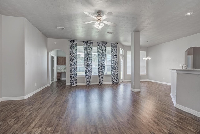 8014 Pine Wood Ct, Baytown, TX 77523 - unfurnished living room with arched walkways, plenty of natural light, ceiling fan, dark wood-style flooring, and a textured ceiling
