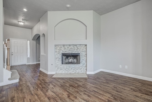 8014 Pine Wood Ct, Baytown, TX 77523 - unfurnished living room with wood finished floors, arched walkways, a fireplace, and a textured ceiling