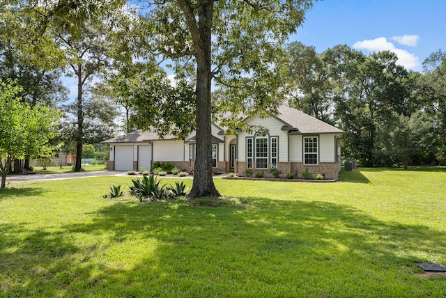 9119 Bush Buck Ln, Conroe, TX 77303 - single story home with concrete driveway, brick siding, a front lawn, an attached garage, and a shingled roof