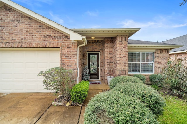 1727 Caldbeck Ln, Fresno, TX 77545 - view of exterior entry featuring brick siding, an attached garage, a shingled roof, and driveway