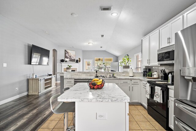 1727 Caldbeck Ln, Fresno, TX 77545 - kitchen with appliances with stainless steel finishes, vaulted ceiling, a peninsula, a center island, and backsplash