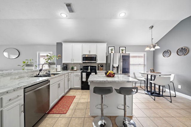 1727 Caldbeck Ln, Fresno, TX 77545 - kitchen with stainless steel appliances, vaulted ceiling, tasteful backsplash, a kitchen island, and light tile patterned floors