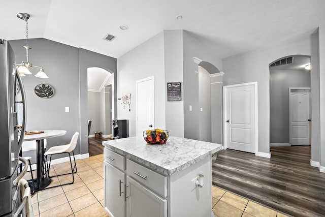 1727 Caldbeck Ln, Fresno, TX 77545 - kitchen with arched walkways, light tile patterned floors, freestanding refrigerator, a kitchen island, and light countertops