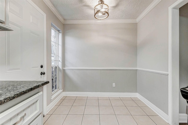 6402 Del Monte Dr Unit 20, Houston, TX 77057 - unfurnished dining area with a textured ceiling, a wainscoted wall, crown molding, and light tile patterned flooring