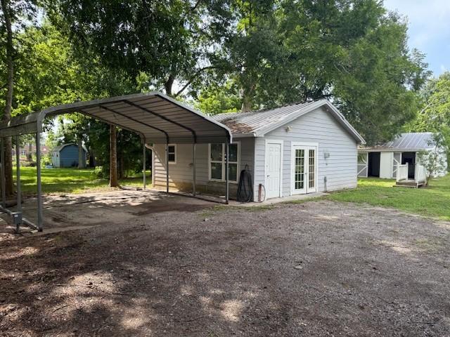 804 Tovrea Rd, Alvin, TX 77511 - rear view of house featuring a carport, dirt driveway, a metal roof, and a storage unit