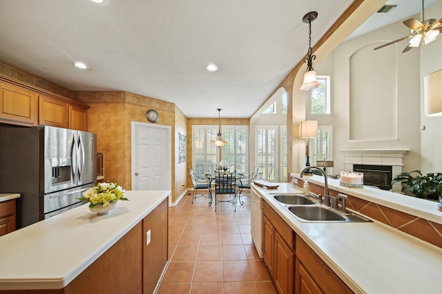 3207 Summerwind Ct, Pearland, TX 77584 - kitchen with stainless steel refrigerator with ice dispenser, brown cabinets, light countertops, light tile patterned floors, and pendant lighting