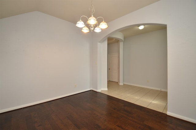 21514 Colton Cove Dr, Houston, TX 77095 - empty room with lofted ceiling, arched walkways, wood finished floors, and a chandelier
