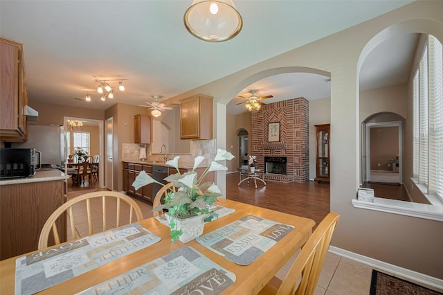 21619 Oakcreek Ct, Katy, TX 77450 - dining space with a ceiling fan, a brick fireplace, light tile patterned floors, and arched walkways