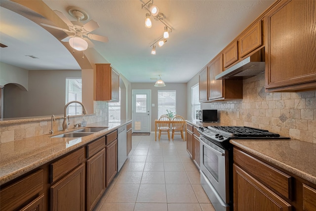 21619 Oakcreek Ct, Katy, TX 77450 - kitchen with stainless steel appliances, under cabinet range hood, a ceiling fan, arched walkways, and brown cabinets